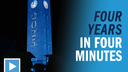 UNC-Chapel Hill's Morehead-Patterson Bell Tower lit Carolina Blue in the dark the night of Commencement and projected white text reading 