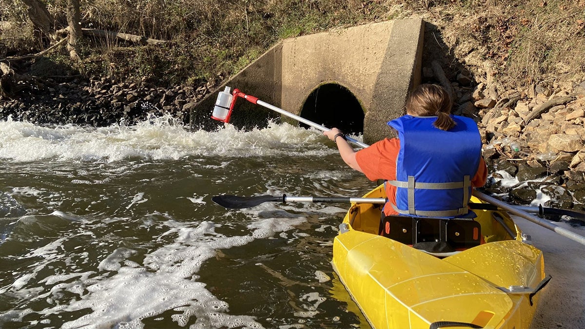 Emily Crawford collecting water specimens while in a canoe.