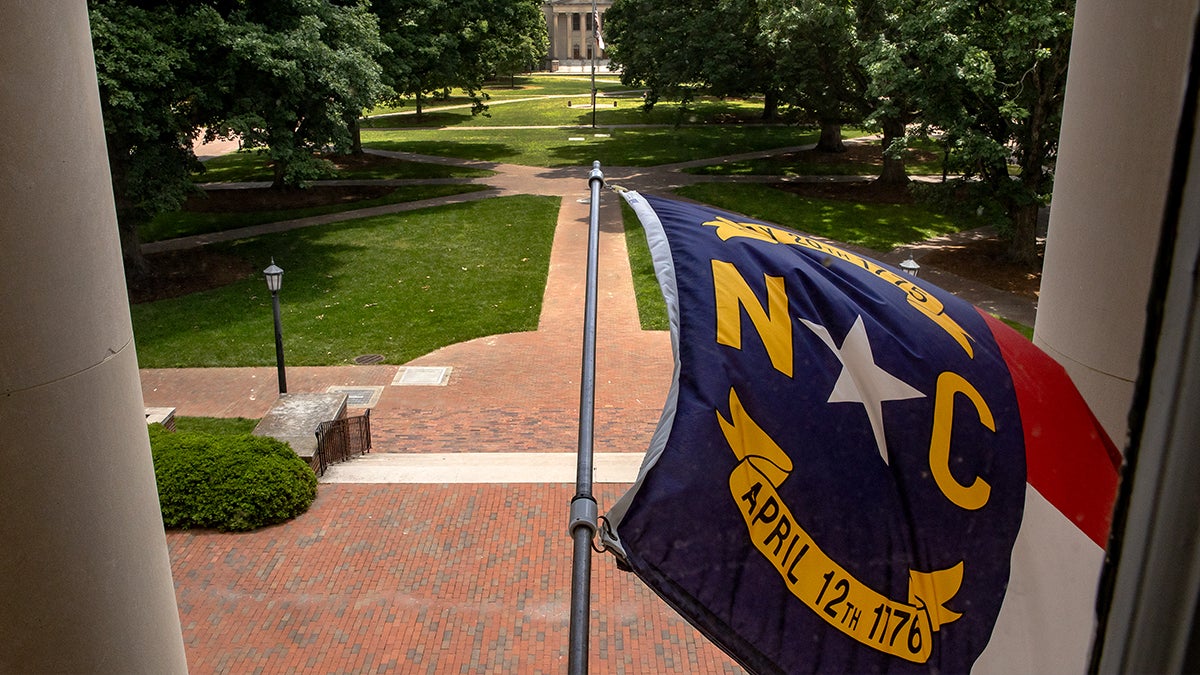 North Carolina flag hanging from South Building overlooking Polk Place