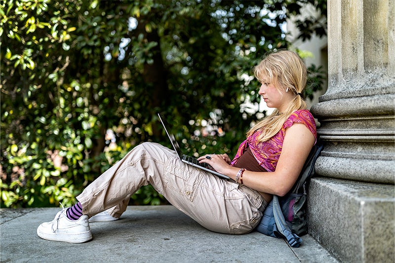 A student using her laptop outside Wilson Library on the campus of UNC-Chapel Hill.