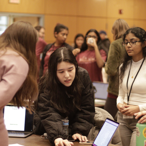 Group of Pearl Hacks attendees gathering around a laptop to examine a project.
