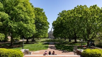 Three students sitting on the steps of South Building overlooking main campus quad.