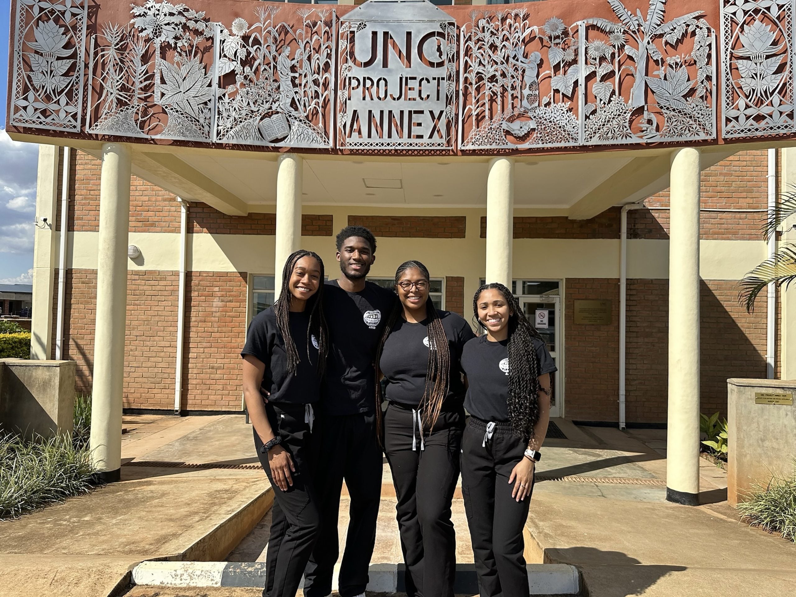 Dentistry students posing in front of building with sign reading "UNC Project Annex".